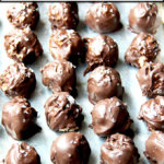 A sheet pan lined with chocolate-covered peanut butter balls.