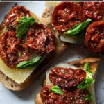 Three toasts with oven-dried tomatoes, cheese, and basil