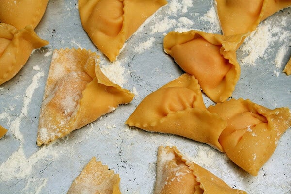 Shaped uncooked pumpkin ravioli on a sheet pan. 