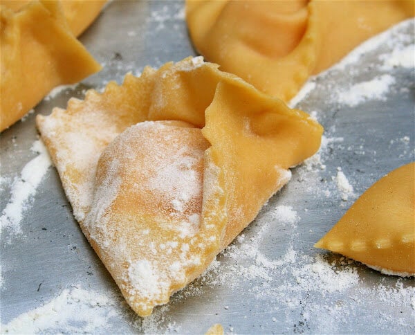 A shaped uncooked pumpkin ravioli on a sheet pan. 