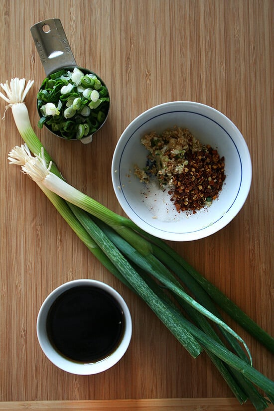 A board of scallions, spices, and soy sauce. 