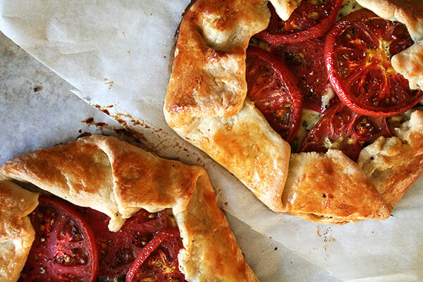 Premium Photo  Homemade galette or savory pie with red and yellow tomatoes  and basil on old newspaper or parchment paper. top view.