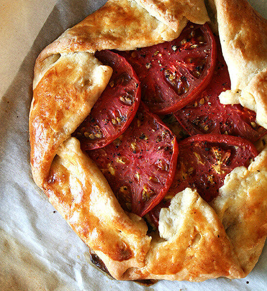 Premium Photo  Homemade galette or savory pie with red and yellow tomatoes  and basil on old newspaper or parchment paper. top view.