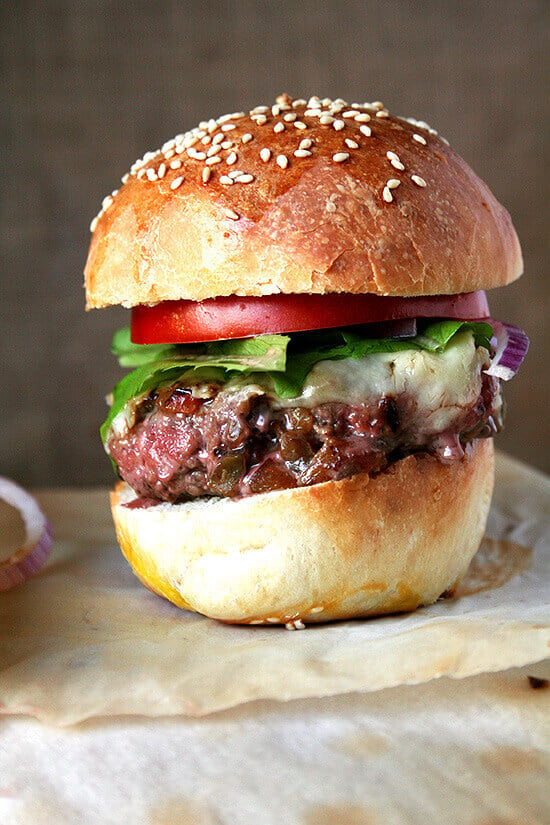 A pan-seared burger with secret sauce, pickled onions, and tomato on homemade brioche.