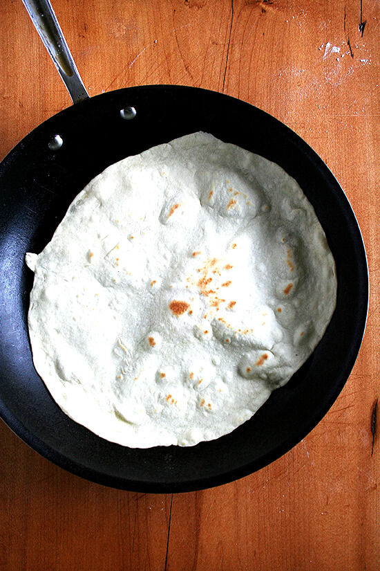 A skillet holding a homemade flour tortilla. 