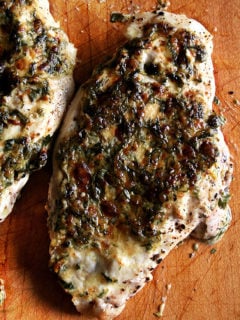 Broiled tarragon chicken breasts on a board.