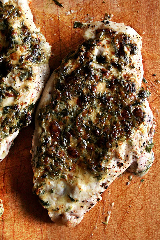 A board with broiled tarragon chicken breasts on top. 