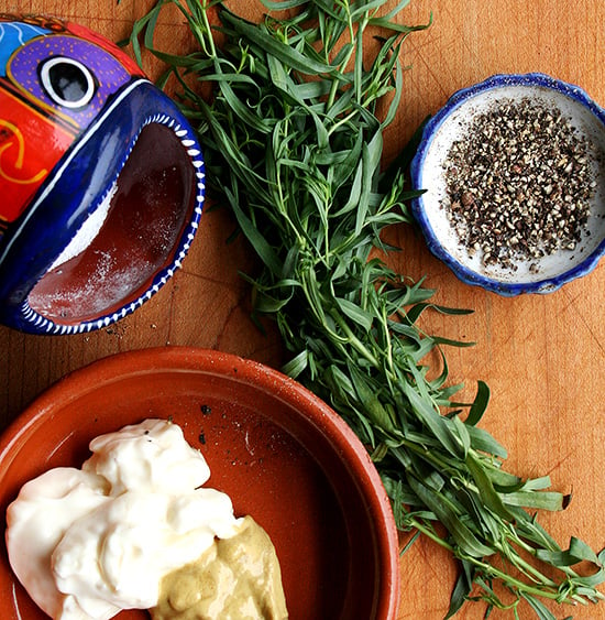 mustard, mayonnaise, tarragon, salt, and pepper on a board.