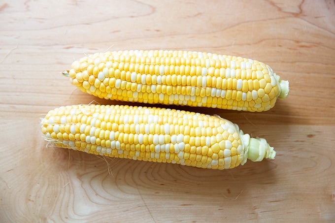 Two ears of corn on a countertop. 