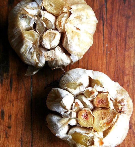 An overhead shot of two heads of roasted garlic.