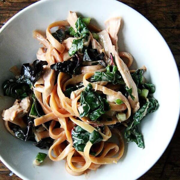 A bowl of sesame noodles with swiss chard.