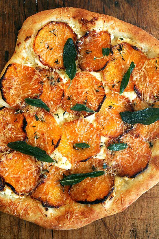 A roasted butternut squash and crispy sage pizza on a board. 