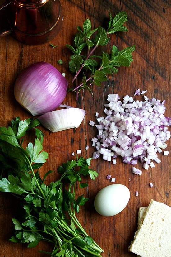 A board with mint and diced red onion. 
