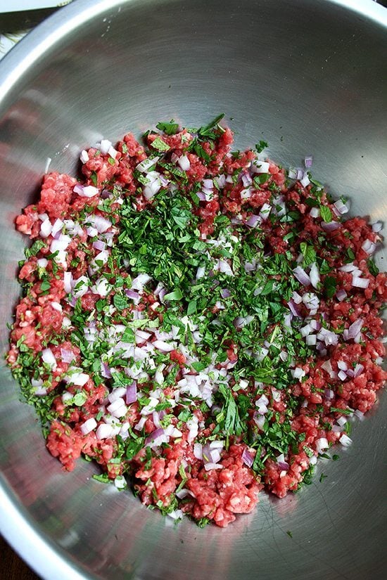 A bowl with all of the ingredients to make lamb meatballs.