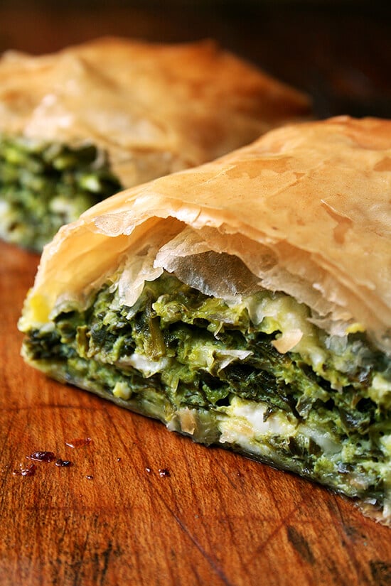 A halved spanakopita strudel on a board.