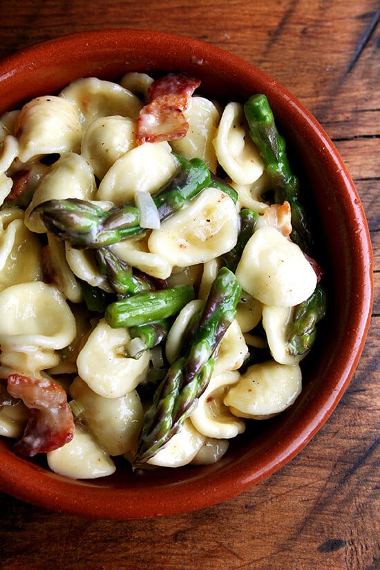 A bowl of pasta carbonara with asparagus. 