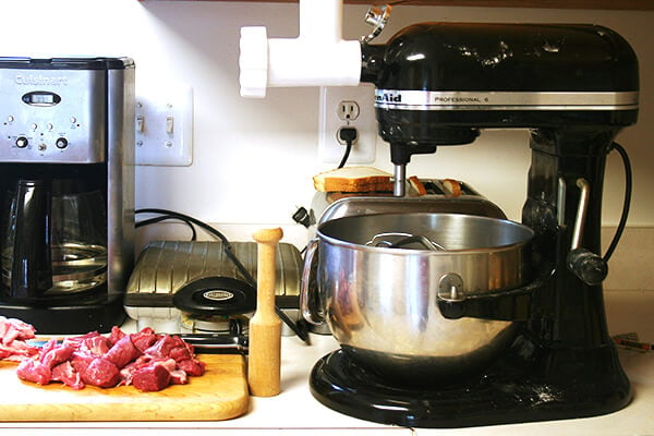 A stand mixer with a meat grinder attached. 