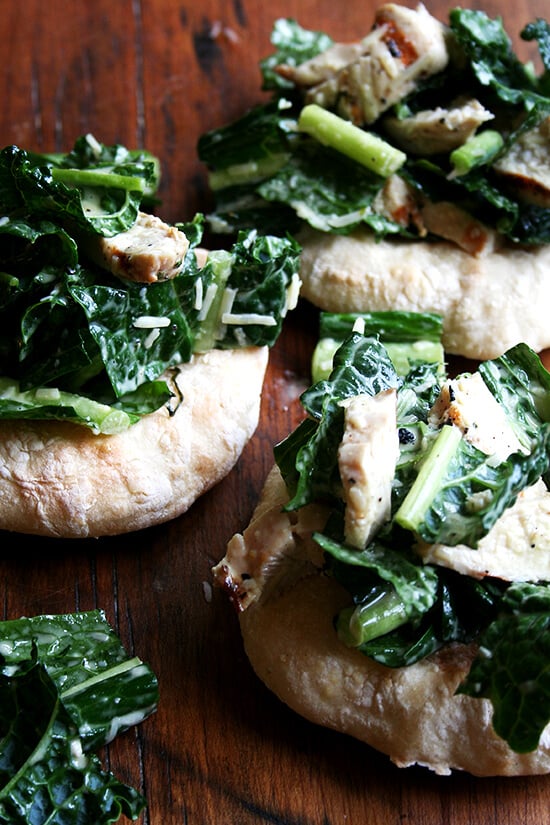 I'm planning a dinner party and thought it might be fun to make little flatbreads — "piadines" I saw them called — piled high with caesar salad — boring, I know, but perhaps made interesting by kale — tossed with sliced grilled chicken breasts — boring, I know, but chicken caesar kale salad is safe. I love this kind of thing, when bread and vegetable and meat are all wrapped up in one casual, fun, summery, light dish. // alexandracooks.com