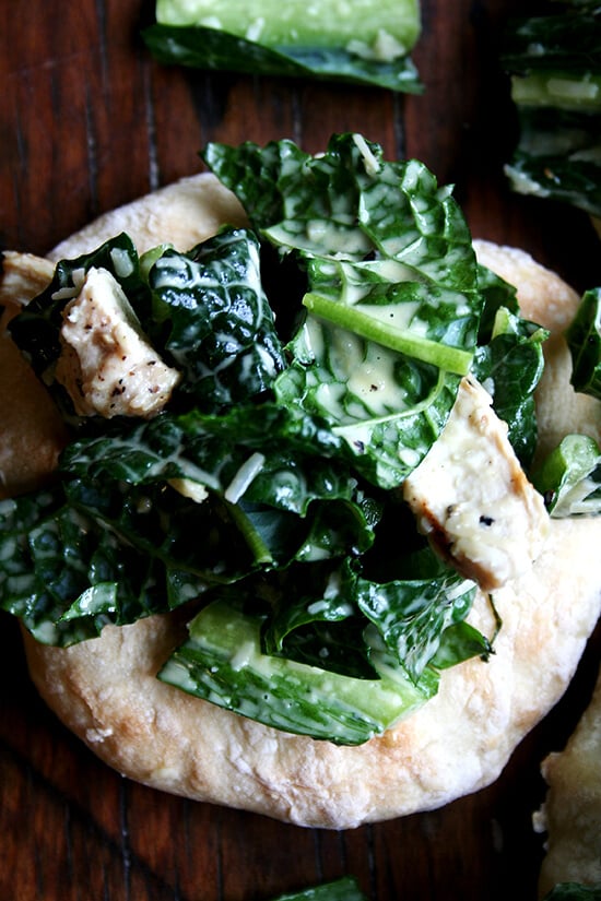 I'm planning a dinner party and thought it might be fun to make little flatbreads — "piadines" I saw them called — piled high with caesar salad — boring, I know, but perhaps made interesting by kale — tossed with sliced grilled chicken breasts — boring, I know, but chicken caesar kale salad is safe. I love this kind of thing, when bread and vegetable and meat are all wrapped up in one casual, fun, summery, light dish. // alexandracooks.com