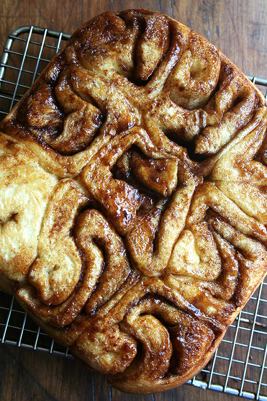 A pan of cinnamon rolls turned out onto a cooling rack.