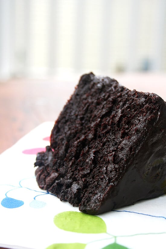 A of slice of double chocolate cake with black velvet icing on a napkin, ready to eat. 