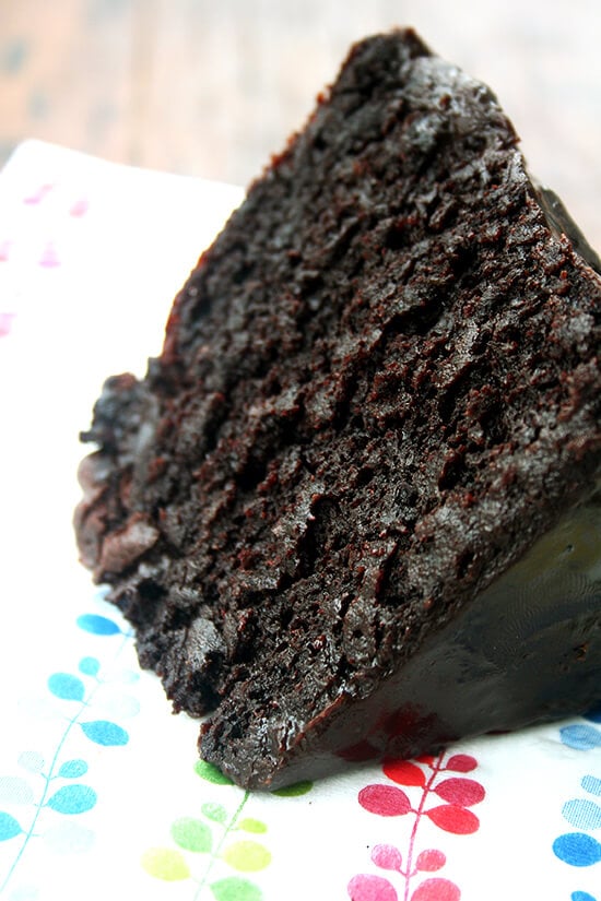 A slice of double chocolate cake with black velvet icing on a napkin. 