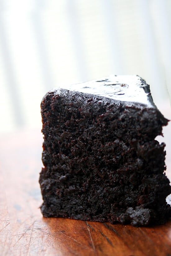 A slice of double chocolate cake standing on a board. 