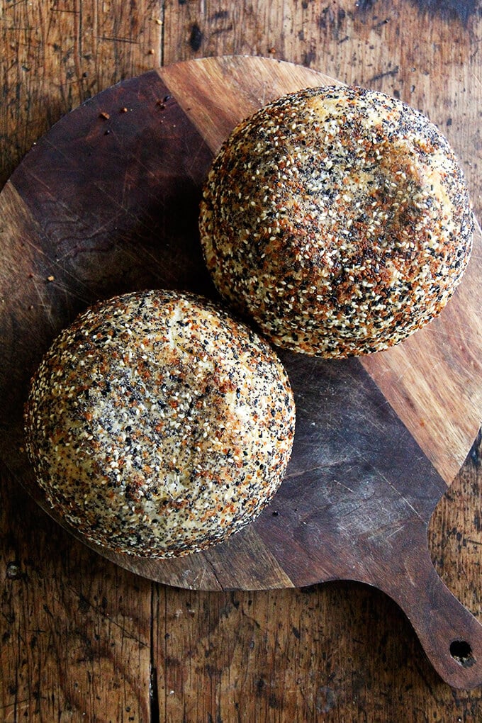 Overhead view of two loaves of peasant bread with everything bagel seasoning on cutting board