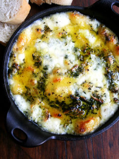 A cast iron skillet filled with baked fontina with rosemary and thyme.