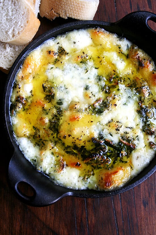 A cast iron skillet filled with baked fontina with rosemary and thyme. 