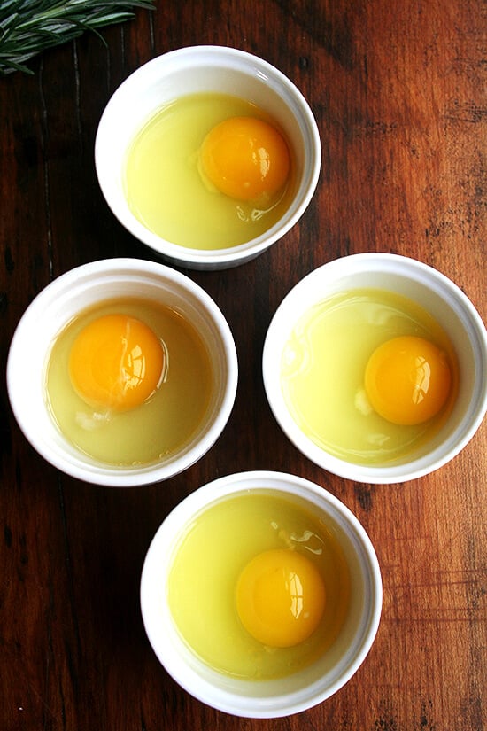 4 ramekins each holding an egg.