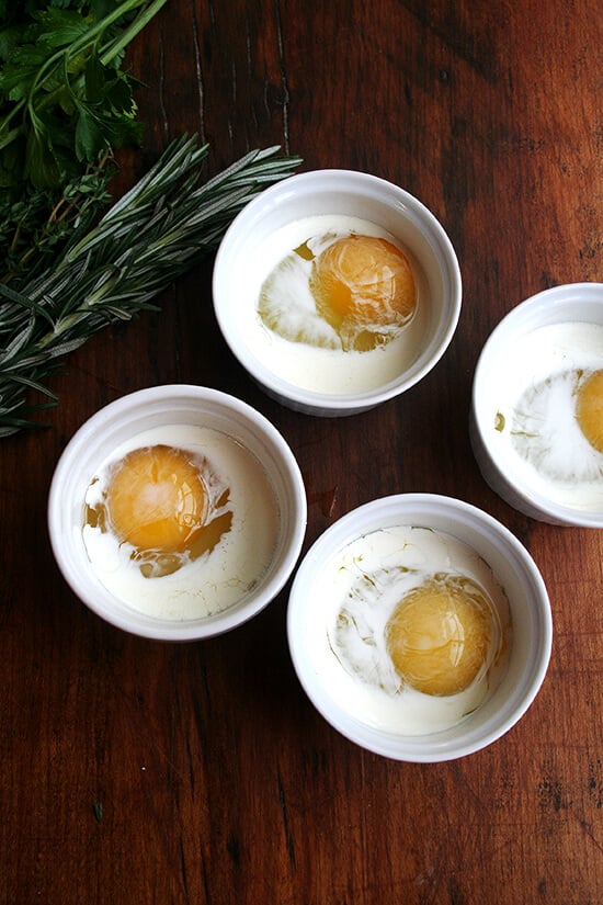 4 ramekins each holding an egg and cream.