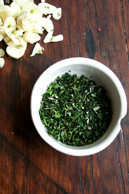 minced herbs and sliced garlic on a board