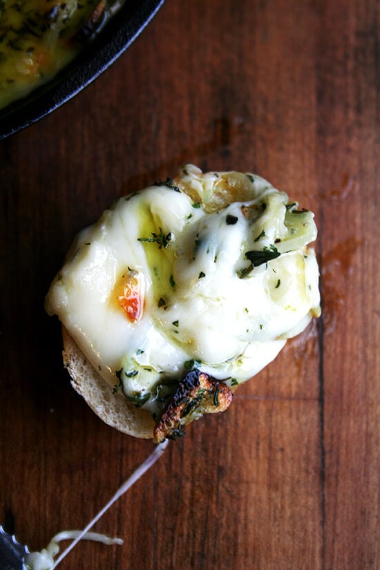 A bite of baked fontina with rosemary and thyme on bread. 