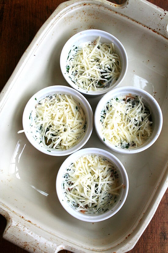 4 ramekins, filled with baked eggs, in a baking dish.