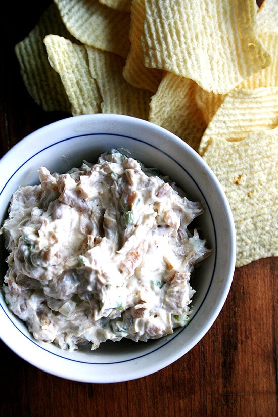 A bowl of real sour cream and onion dip aside Ruffle potato chips. 