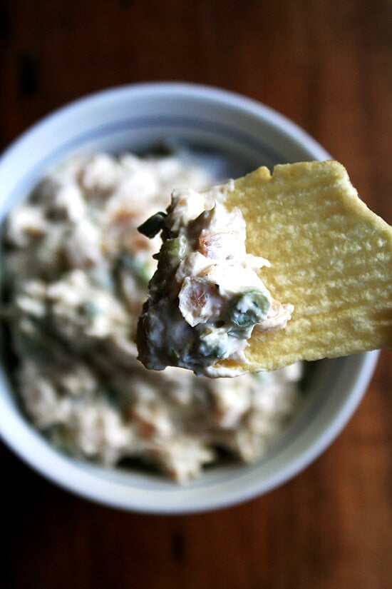 A bowl of real sour cream and onion dip with a Ruffle potato chip.