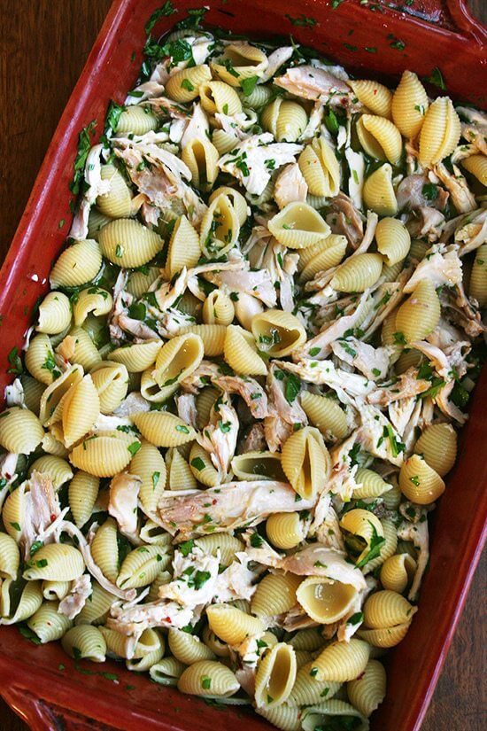 A 9x13-inch pan filled with pasta, chicken, herbs, lemon, and white wine. 