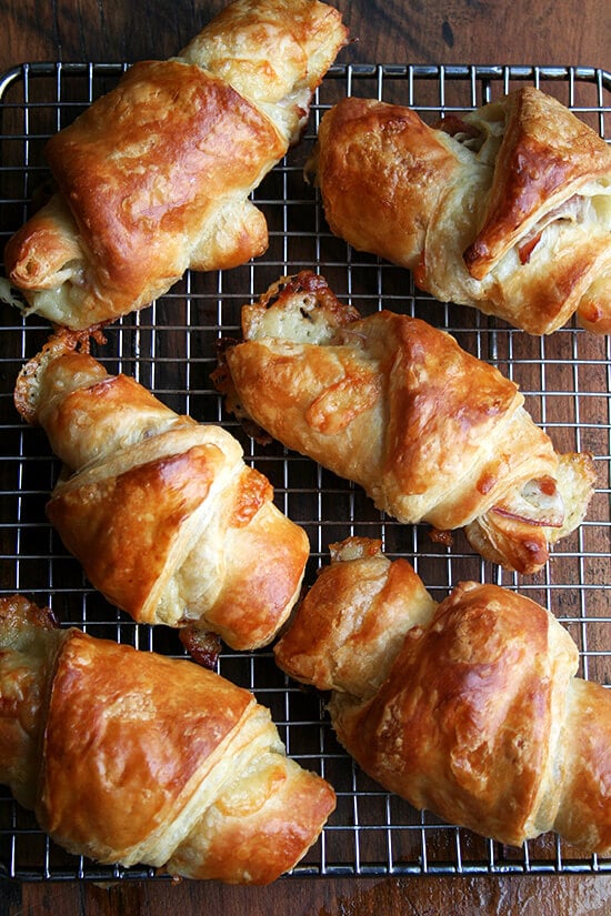 Homemade ham and cheese croissants, cooling on a rack.
