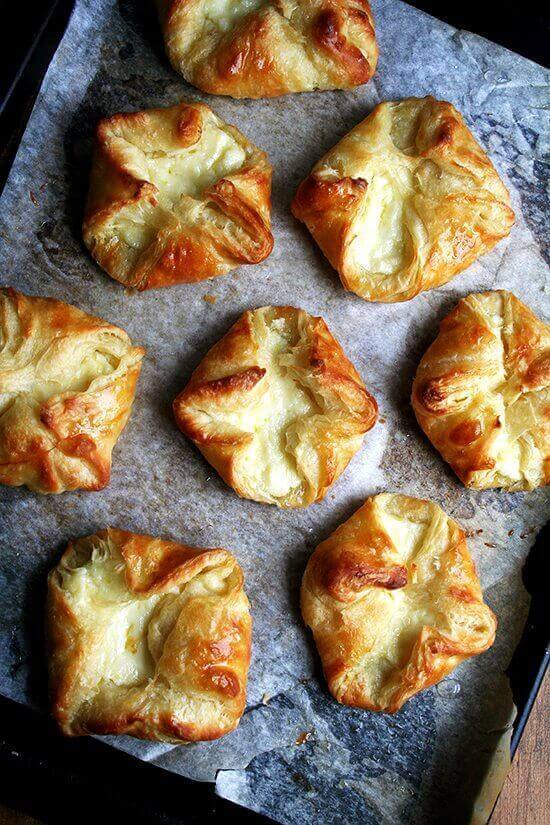 An overhead shot of a sheet pan of 8 freshly baked cheese Danishes.