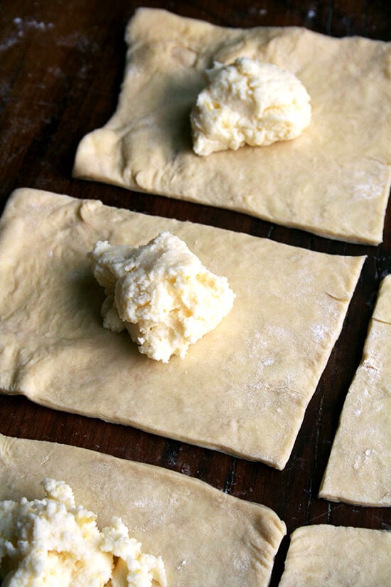 Danish pastry dough cut into 8 squares, filled with the ricotta filling, ready to be pinched. 