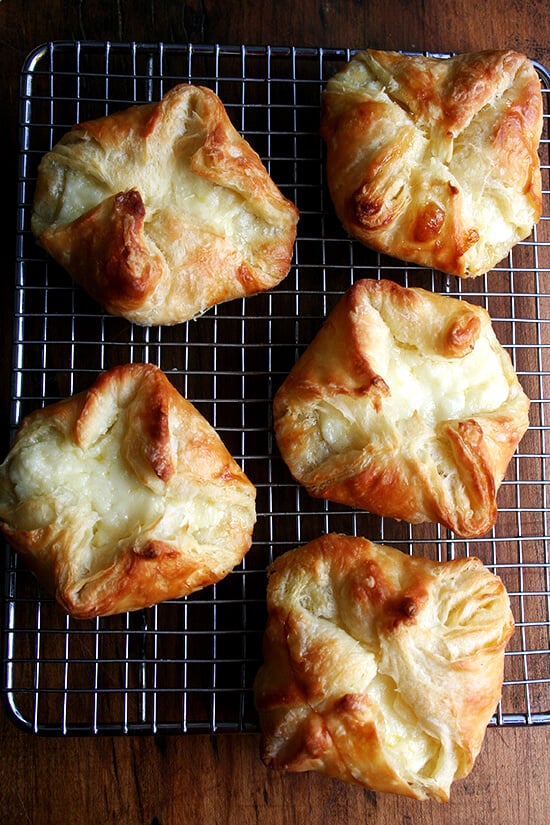 An overhead shot of 5 cheese Danishes on a cooling rack.