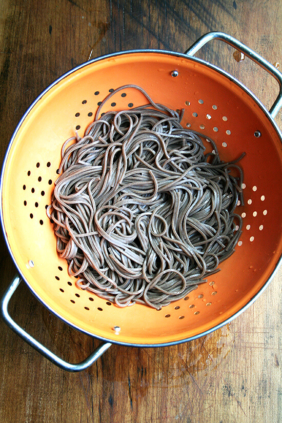 cooked soba noodles draining in a colander 