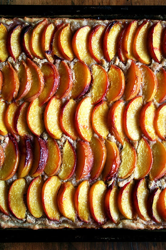 For this peach frangipane tart, my favorite galette dough is used for a sheet-pan tart. After smearing the whole batch of frangipane over its surface and arranging half a dozen sliced peaches over top, the fruit is brushed with melted butter and sprinkled with sugar. Forty minutes later, the tart emerges from the oven, slices of fruit glistening, frangipane bubbling through the crevices. // alexandracooks.com