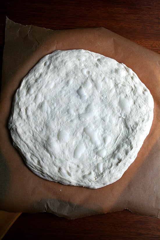 Stretched round of Lahey pizza dough on a pizza peel. 