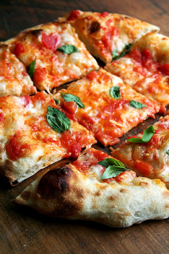 Just-baked Margherita pizza cut into pieces. 