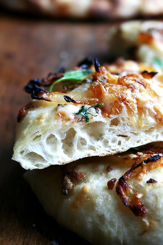 The crust view of a caramelized onion and burrata pizza sprinkled with basil.
