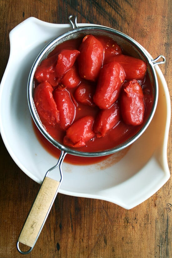 Overhead view of draining the tomatoes in a strainer.