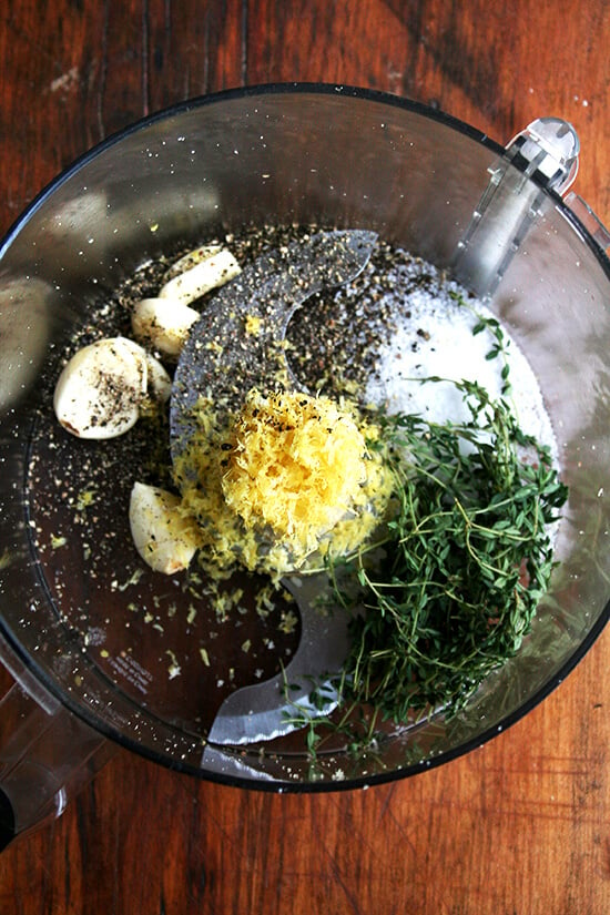 Food processor with lemon zest, garlic, salt, pepper, and thyme — this seasoning mix will flavor the bread crumbs.