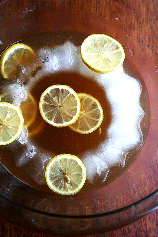 A punch bowl filled with Philadelphia fish house punch, ice ring, and sliced lemons. 